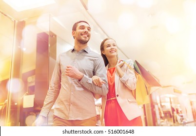 Sale, Consumerism And People Concept - Happy Young Couple With Shopping Bags Walking In Mall