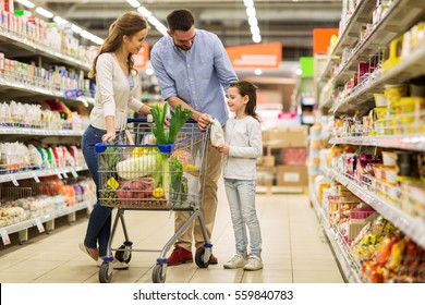 Sale, Consumerism And People Concept - Happy Family With Child And Shopping Cart Buying Food At Grocery Storeor Supermarket