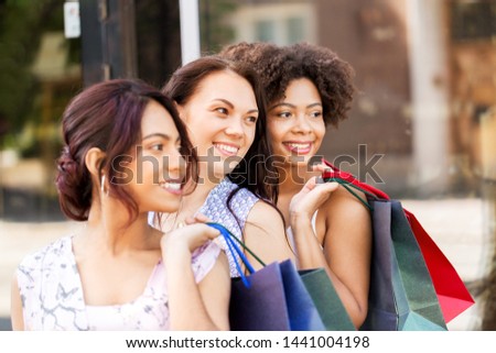 sale, consumerism and people concept - happy young women with shopping bags on city street