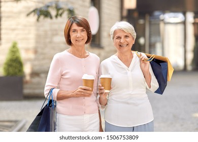 Sale, Consumerism And People Concept - Two Senior Women Or Friends With Shopping Bags Drinking Takeaway Coffee On Tallinn City Street