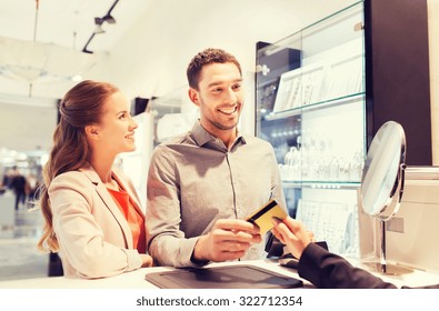 sale, consumerism, shopping and people concept - happy couple with credit card at jewelry store in mall