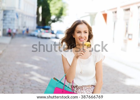 sale, consumerism, summer and people concept - happy young woman with shopping bags and ice cream on city street