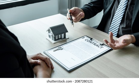Sale Estate agent are presenting home loan to customer to decision signing contract to rental house insurance with approved property form. - Shutterstock ID 2087280121
