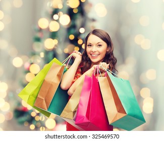 sale, gifts, holidays and people concept - smiling woman with colorful shopping bags over living room and christmas tree background