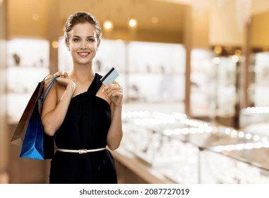 Sale, Luxury And People Concept - Smiling Woman In Dress With Shopping Bags And Credit Card Over Jewelry Store Background