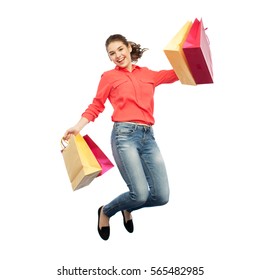 Sale, Motion And People Concept - Smiling Young Woman With Shopping Bags Jumping In Air Over White Background