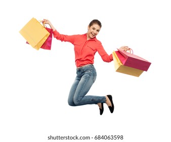 Sale, Motion And People Concept - Smiling Young Woman With Shopping Bags Jumping In Air Over White Background