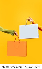 Sale offer. Black Friday. Shopping discount. Closeup of two girl's hand holding purchase bags isolated on bright yellow background. concept of fashion, online shopping, salesperson. copy space. ad