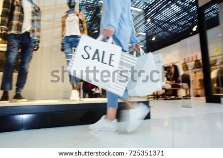 Sale paperbags carried by hurrying shopper choosing new stylish clothes on black friday