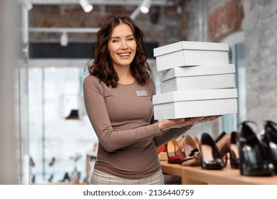 Sale, Shopping And Business Concept - Happy Female Shop Assistant Or Saleswoman Holding Three Shoe Boxes Over Store Background