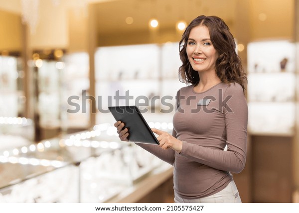sale, shopping and business concept - happy\
female shop assistant with tablet pc computer name tag over jewelry\
store background