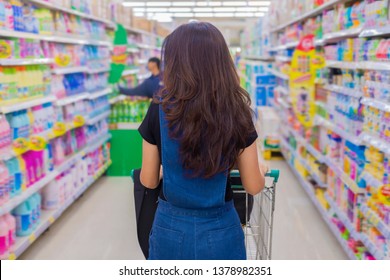 Sale, Shopping, Consumerism And People Concept - Back Side Of Woman With Shopping Trolley At Grocery Store Or Supermarket Aisle.  