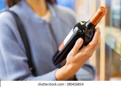 Sale, Shopping, Consumerism And People Concept - Happy Young Woman Choosing And Buying Wine In Market Or Liquor Store