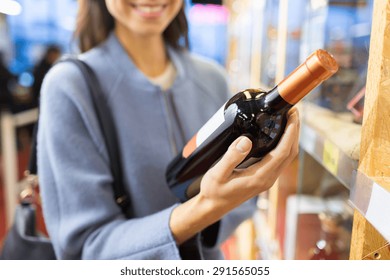 Sale, Shopping, Consumerism And People Concept - Happy Young Woman Choosing And Buying Wine In Market Or Liquor Store