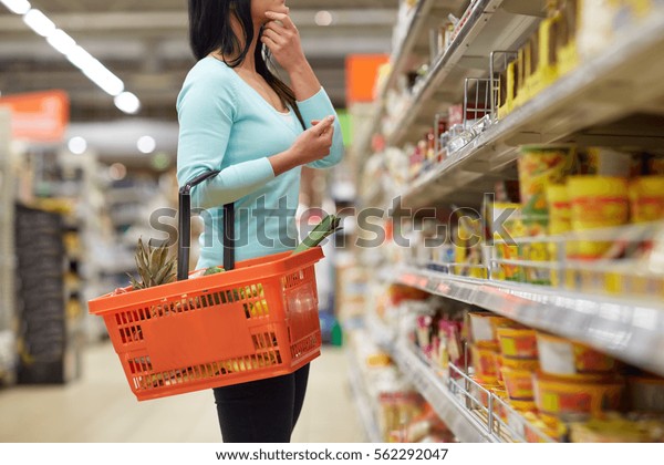 sale, shopping,\
consumerism and people concept - woman with food basket at grocery\
store or supermarket
