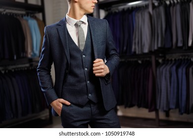 sale, shopping, fashion, style and people concept - elegant young man choosing and trying jacket on in mall or clothing store - Powered by Shutterstock