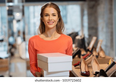 sale, shopping and people concept - happy young woman or shop assistant with shoe boxes at store