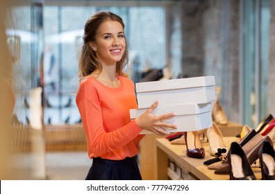 sale, shopping and people concept - happy young woman or shop assistant with shoe boxes at store
