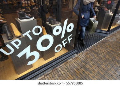 Sale Sign And Discount Numbers On Shop Window Of Shoe Store And Customer Leaving