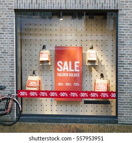 sale signs in display window of clothing store and part of bicycle on the street