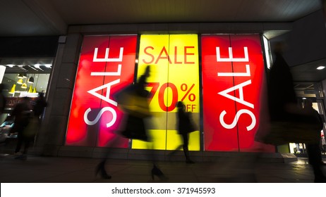 Sale signs in shop window, include silhouette of shoppers - Shutterstock ID 371945593