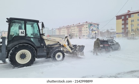 Salekhard, Yamalo-Nenets Autonomous Okrug (Yamal), Russia, April 06, 2022: Heavy Snowstorm And Wind In The City. A Tractor Pulls A Car Stuck In Deep Snow.