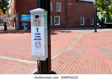 Salem, MA, USA, 9.13.21 - A long, thing bin that's attached to a light pole in historic Salem. it reads "Park your butt" and has an arrow facing a hole meant for disposing cigarette butts.