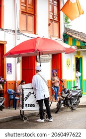 SALENTO, COLOMBIA - JULY 2021. Street Vendor Of Traditional Aborrajados Walking Along The Real Street In The Beautiful Small Town Of Salento