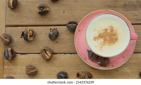 Salep and chestnuts in pink coffee mug on wooden table. Advertising flyers
