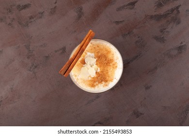 Salep or Sahlep in cup on textured brown surface, top view. Turkish hot drink with cinnamon and spicy. Selective focus, copy space.