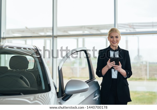 sales agent\
using tablet in car dealership\
showroom