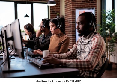 Sales Assistant Answering Helpline Call From Client At Helpdesk, Working At Customer Care Support Center. Asian Operator Giving Telemarketing Assistance On Remote Telephony Network.