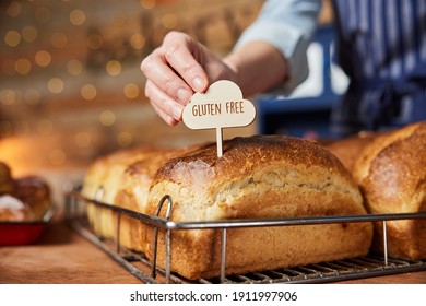 Sales Assistant In Bakery Putting Gluten Free Label Into Freshly Baked Baked Sourdough Loaves Of Bread