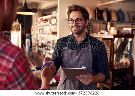 Sales Assistant With Credit Card Reader On Digital Tablet