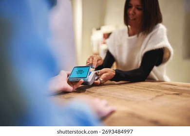 Sales assistant processing mobile payment at store counter