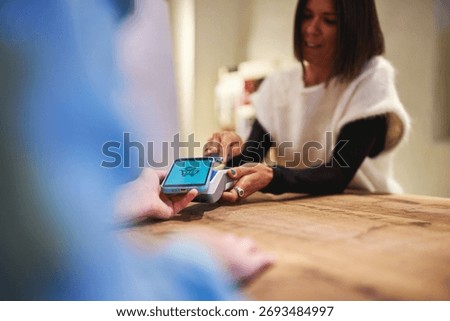 Sales assistant processing mobile payment at store counter