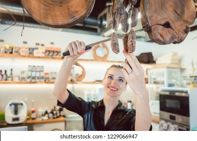 Sales Clerk In Deli Cutting Sausages To Sell Them To Customers