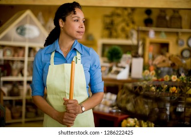 Sales Clerk Standing In Store Holding Broom