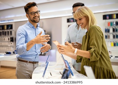 Sales consultant advises people who chooses new digital devices in store. Professional consultation - Powered by Shutterstock