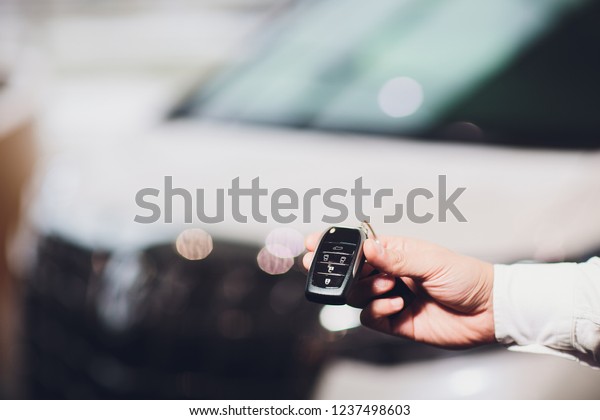 Sales executive giving car key closeup with\
car in background.