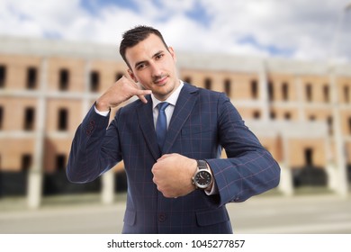 Sales Man Or Realtor Making Call Me You Are Late For Meeting Gesture On New Under Construction Bricks Building Background