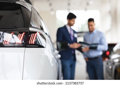 Sales Manager Assisting Male Customer At Auto Dealership, Middle Eastern Man Choosing New Car At Brand New Showroom, Talking To Sales Associate, Checking Brochure, Selective Focus On White Automobile