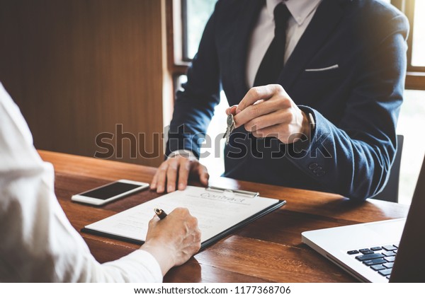 Sales manager filing keys to customer\
after signing rental lease contract of sale purchase agreement,\
concerning mortgage loan offer for and house\
insurance.