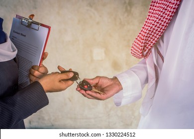 The sales manager holds the clipboard and delivers the car and remote keys to the Muslin businessmen. Come to rent a car or buy a new car or deal leasing car.