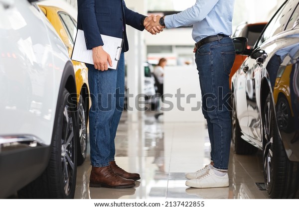 Sales manager\
shaking customer hand, celebrating successful deal, side view,\
cropped. Unrecognizable rich man buying brand new sports automobile\
at luxury showroom,\
panorama