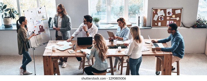 Sales Report. Top View Of Two Modern Young Colleagues Conducting A Business Presentation While Standing In The Board Room