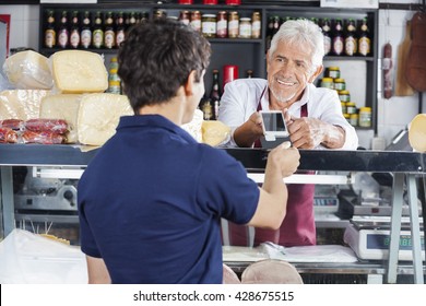 Salesman Accepting Payment From Customer In Cheese Shop