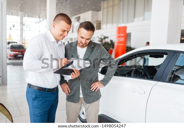 Salesman and buyer\
make out the purchase of\
car