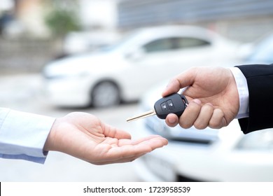 Salesman is carrying the car keys delivered to the customer at the showroom with a low interest offer. Special promotion - Shutterstock ID 1723958539