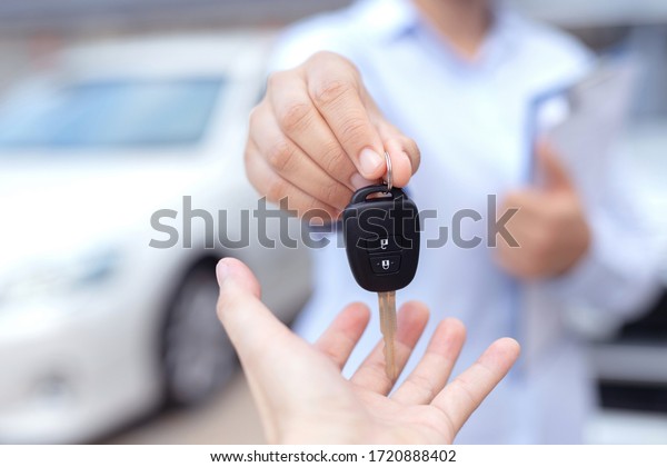 Salesman is\
carrying the car keys delivered to the customer at the showroom\
with a low interest offer. Special\
promotion
